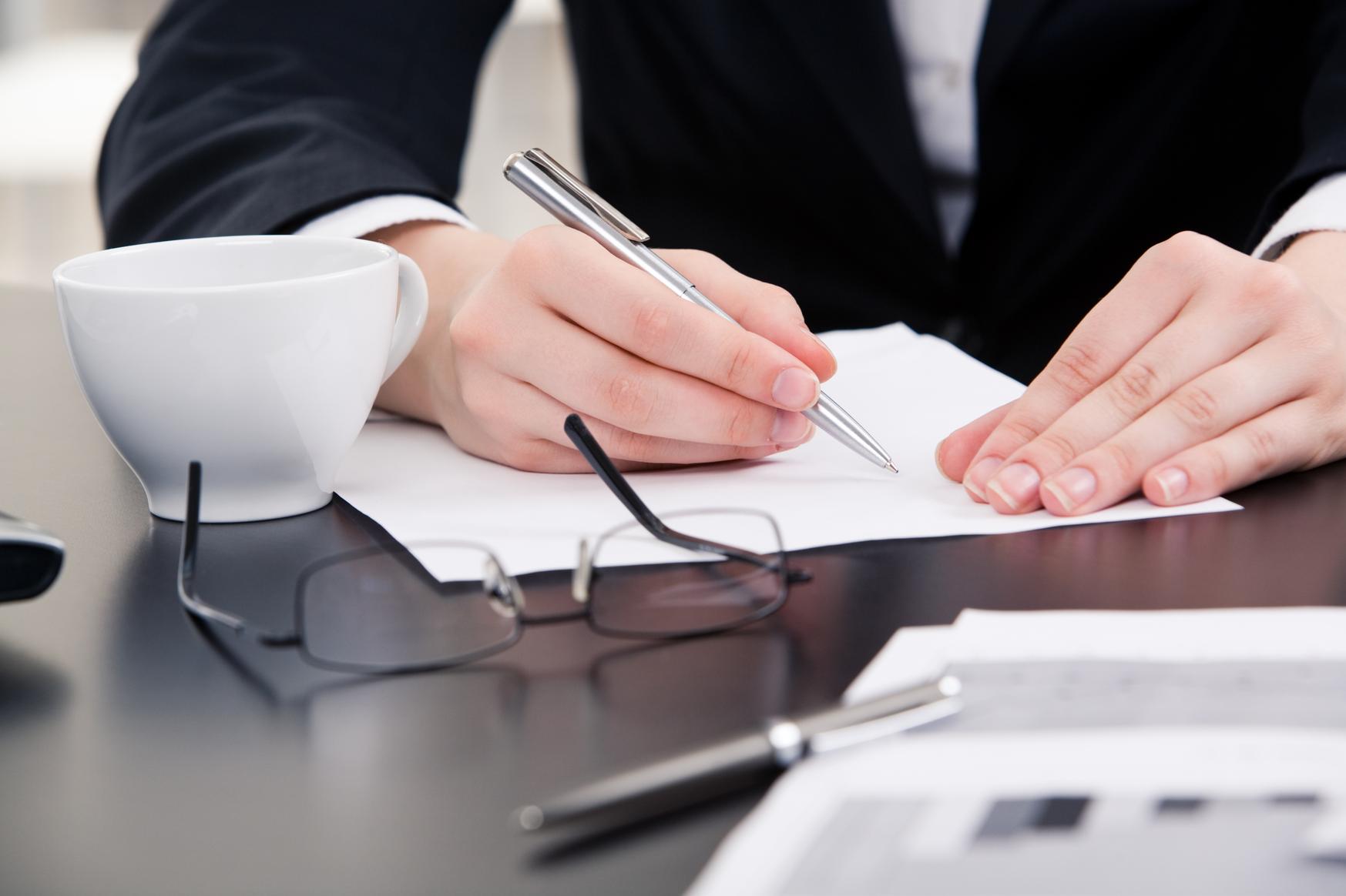 hands holding a pen and writing on paper