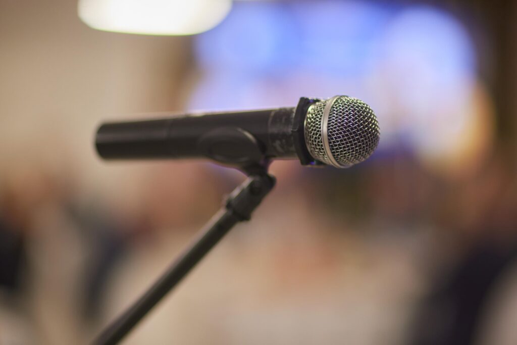 Microphone over the Abstract blurred photo of conference hall or seminar room background