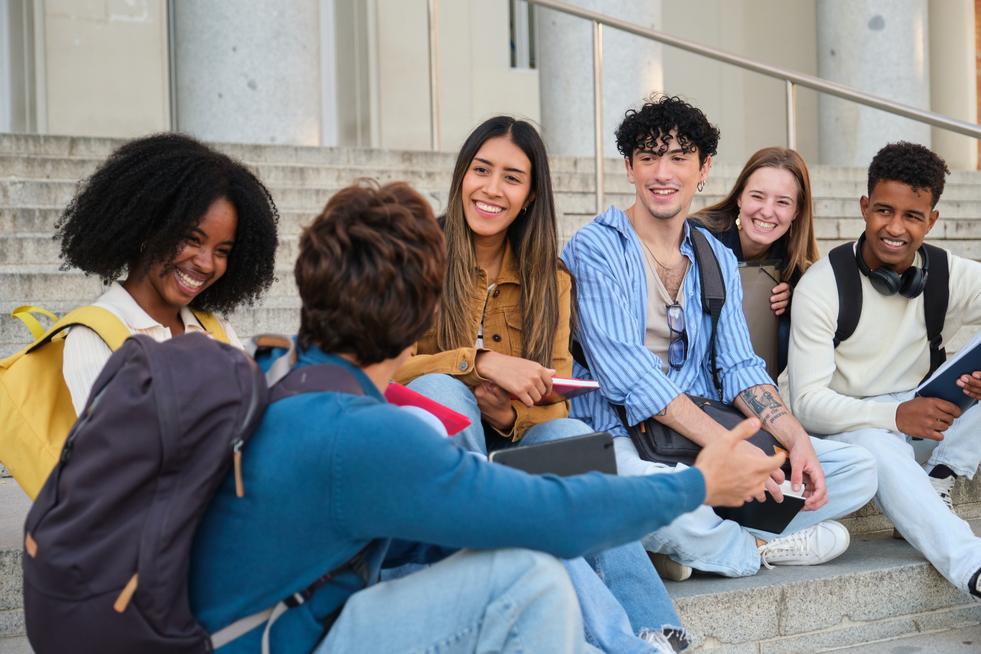 College students sitting, smiling, and discussing on steps outside university building